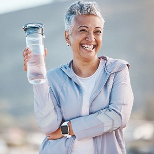 Woman smiling with water bottle on hike outside