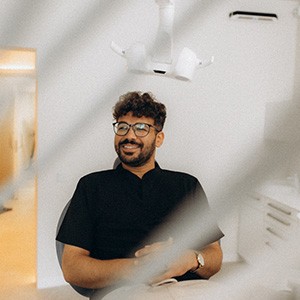 Patient with black glasses smiling in treatment chair