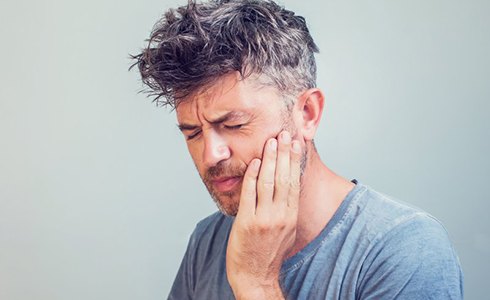 a man touching his cheek due to gum disease